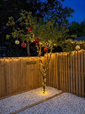 A wooden fence with a sign reading 'The Little White House' and a tree decorated with lights and ornaments. - Standrews- Sleeps4- Familyfriendly- Newlyrenovated (St. Andrews)