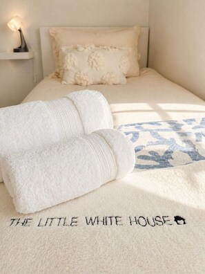 A bedroom with a bed, two rolled-up towels, a patterned throw, and a nightstand with a lamp. - Standrews- Sleeps4- Familyfriendly- Newlyrenovated (St. Andrews)