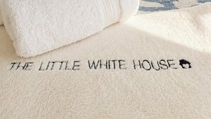 A neatly made bed with a patterned bedspread, a white pillow, and a bedside lamp.