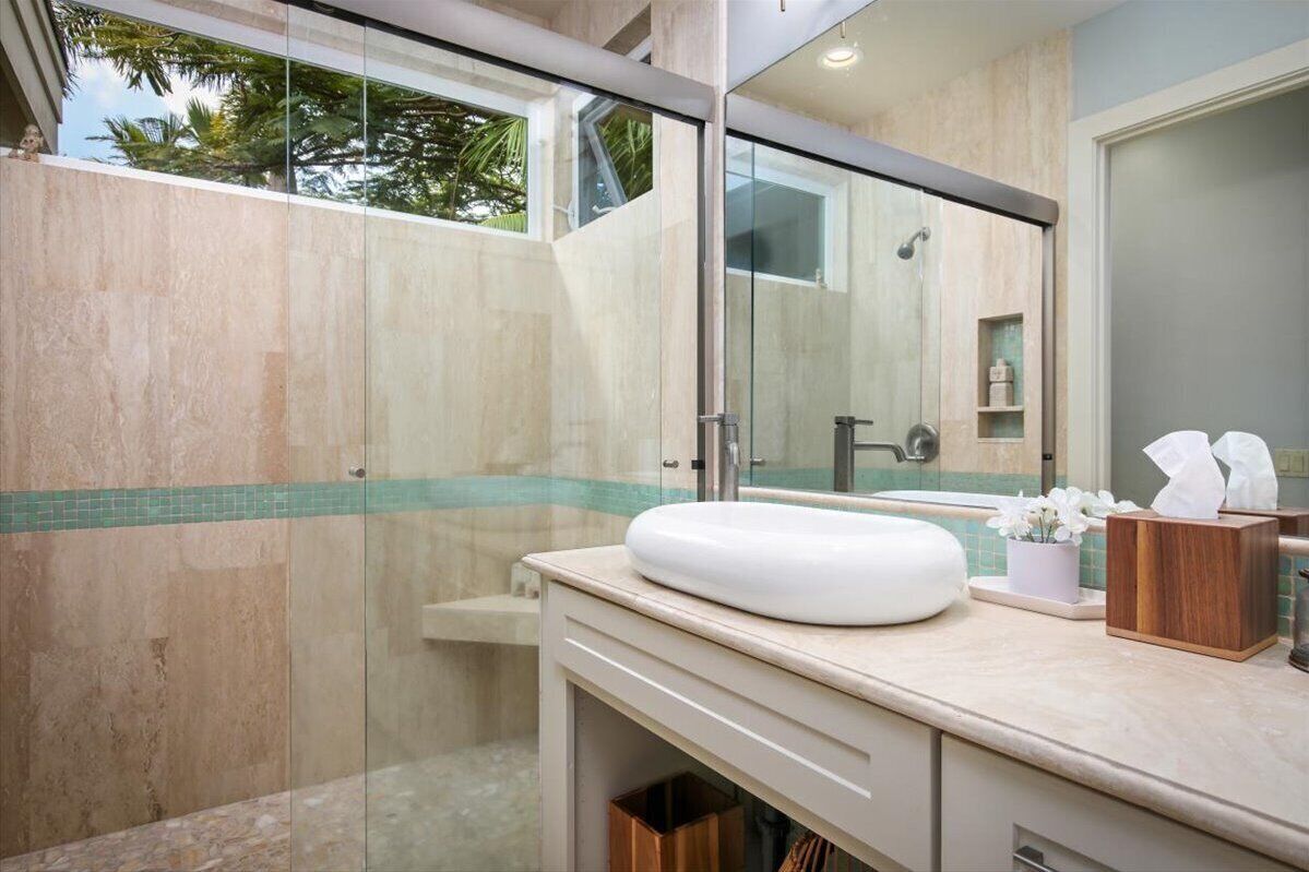 Ein modernes Badezimmer mit einer gläsernen Dusche, einem weißen Waschbecken und einem großen Spiegel.