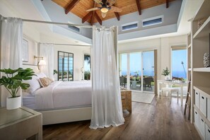 A bedroom with a large bed, a ceiling fan, and a view of the outdoors. - Puuwai Alii Estate: Stunning Luxury Home with Pool, Hot Tub & Ocean Views,AC! (Kailua Kona)