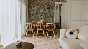 Un espace repas avec un mur en pierre, des chaises en bois, une table et des luminaires suspendus.