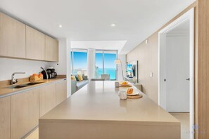 Een moderne keuken met een centraal eiland, een eetgedeelte met uitzicht en een groot raam.