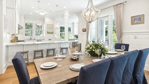 A modern kitchen with white cabinets, a wooden island, and a dining area with blue upholstered chairs. - Seaside "Happy Our" | 6BR |Sleeps 18 | 4 Bikes | Pools (Santa Rosa Beach)