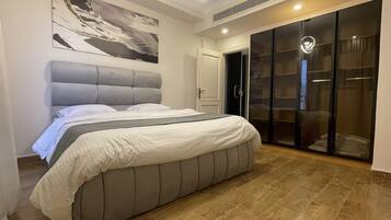 A bedroom with a large bed, a wardrobe, and a painting on the wall.