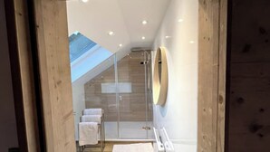 A modern bathroom with a glass shower enclosure, wooden accents, and a skylight. - Splendid 4-star apartment facing the mountains (La Bresse)