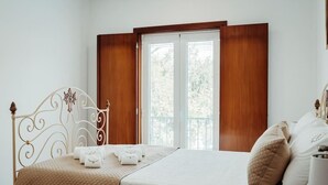 Un lit bien fait, avec une couvre-lit matelassé, une tête de lit décorative et une fenêtre dotée de volets en bois.