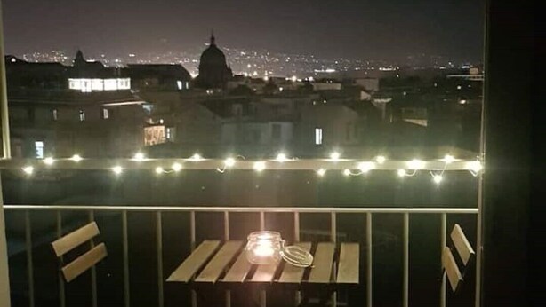 A balcony with a table and chairs, overlooking a cityscape at night. - Montesanto 77 Panoramic house in the historic center (Napoli)