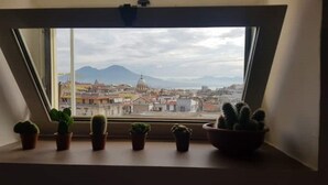 A window with a view of a cityscape, including buildings and mountains. - Montesanto 77 Panoramic house in the historic center (Napoli)