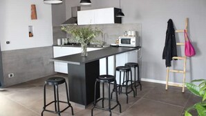 A modern kitchen with a central island, bar stools, a microwave, and pendant lighting. - Montesanto 77 Panoramic house in the historic center (Napoli)