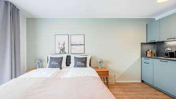 Une chambre d’hôtel moderne avec un grand lit, une petite kitchenette et une vue sur la ville.