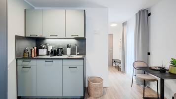 Ett modernt kök med grå skåp, en svart bänkskiva och en matplats med ett bord och stolar.