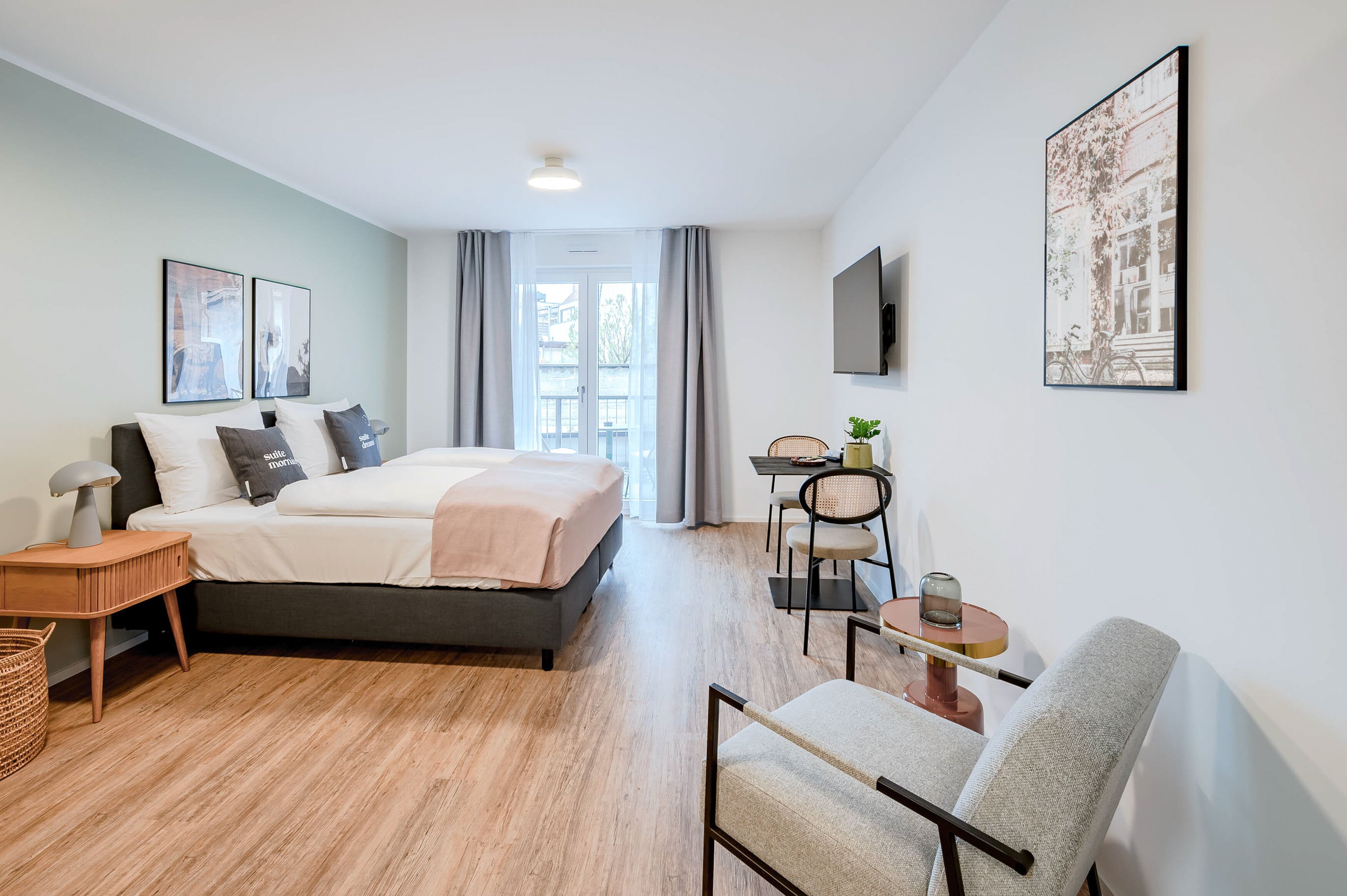 Ein modernes Schlafzimmer mit Bett, Nachttisch, Lampe, Stuhl und einem Tisch mit einer Pflanze.