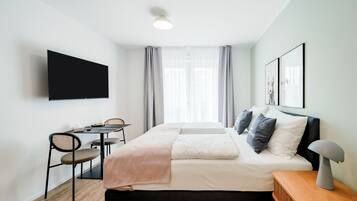 Et moderne hotelværelse med en seng, et natbord og et fjernsyn ophængt på væggen.