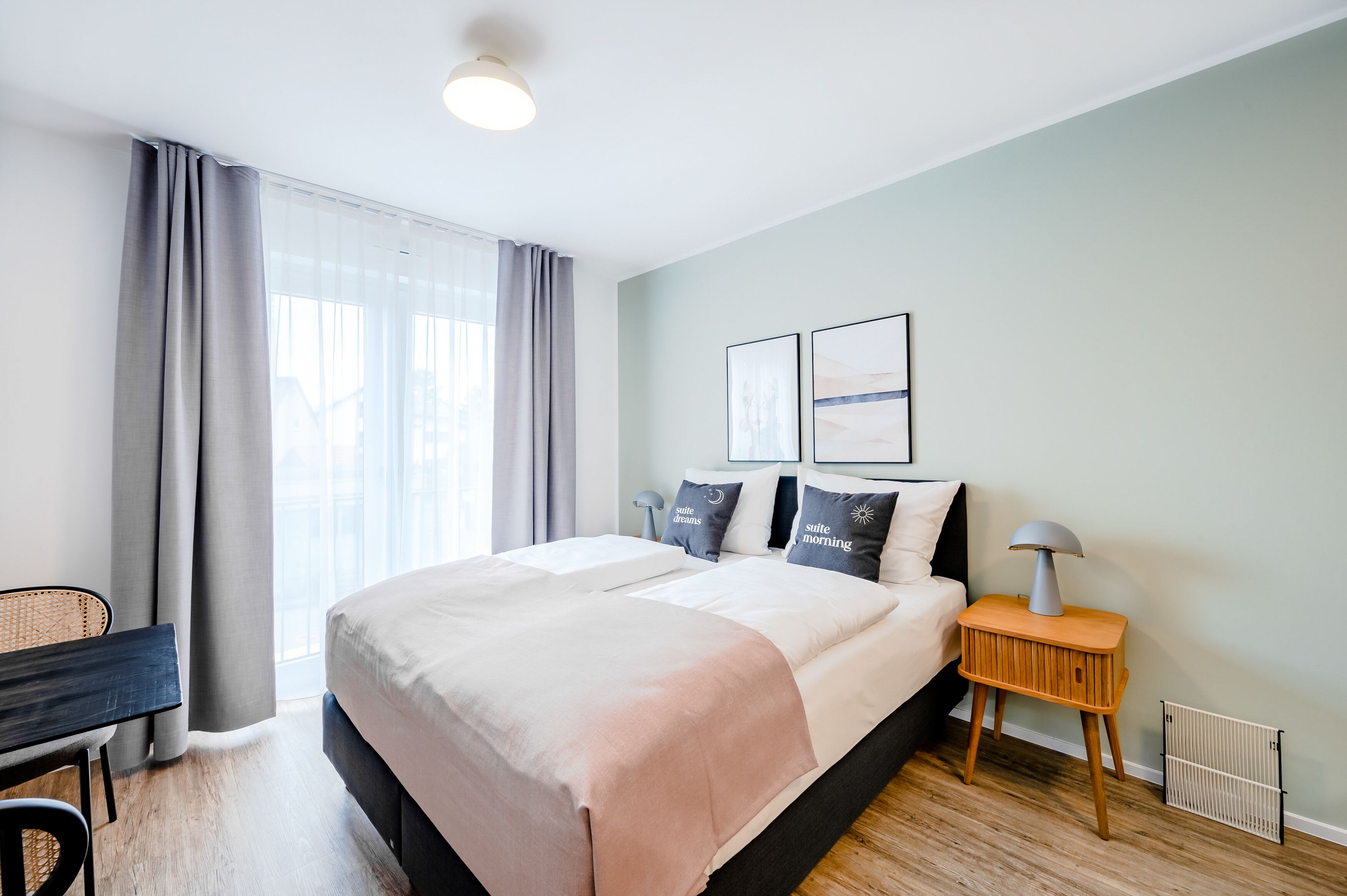 A modern hotel room with a large bed, a desk, and a chair.