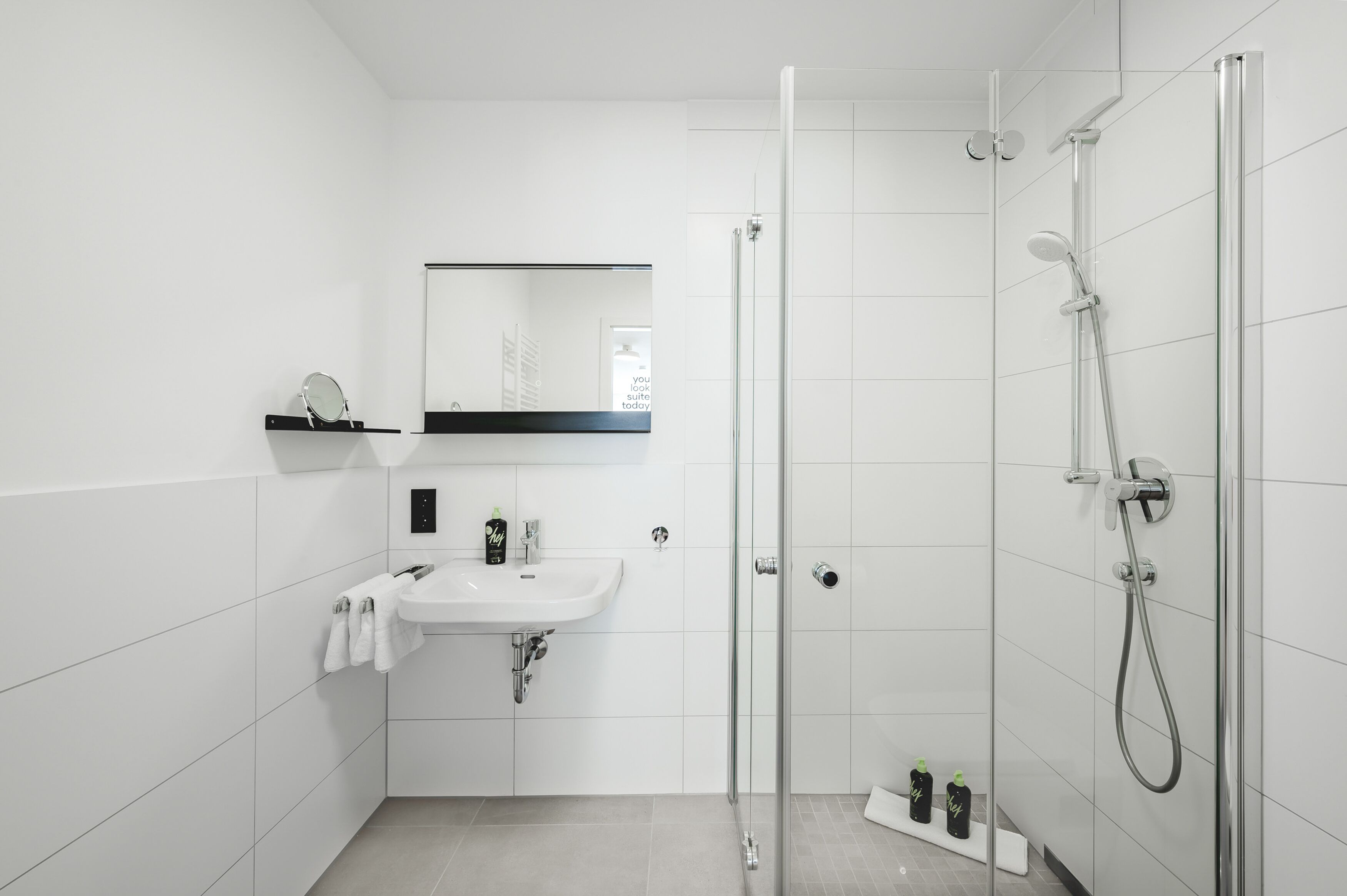 Une salle de bain moderne avec une douche à parois de verre, un lavabo blanc et un miroir au-dessus.