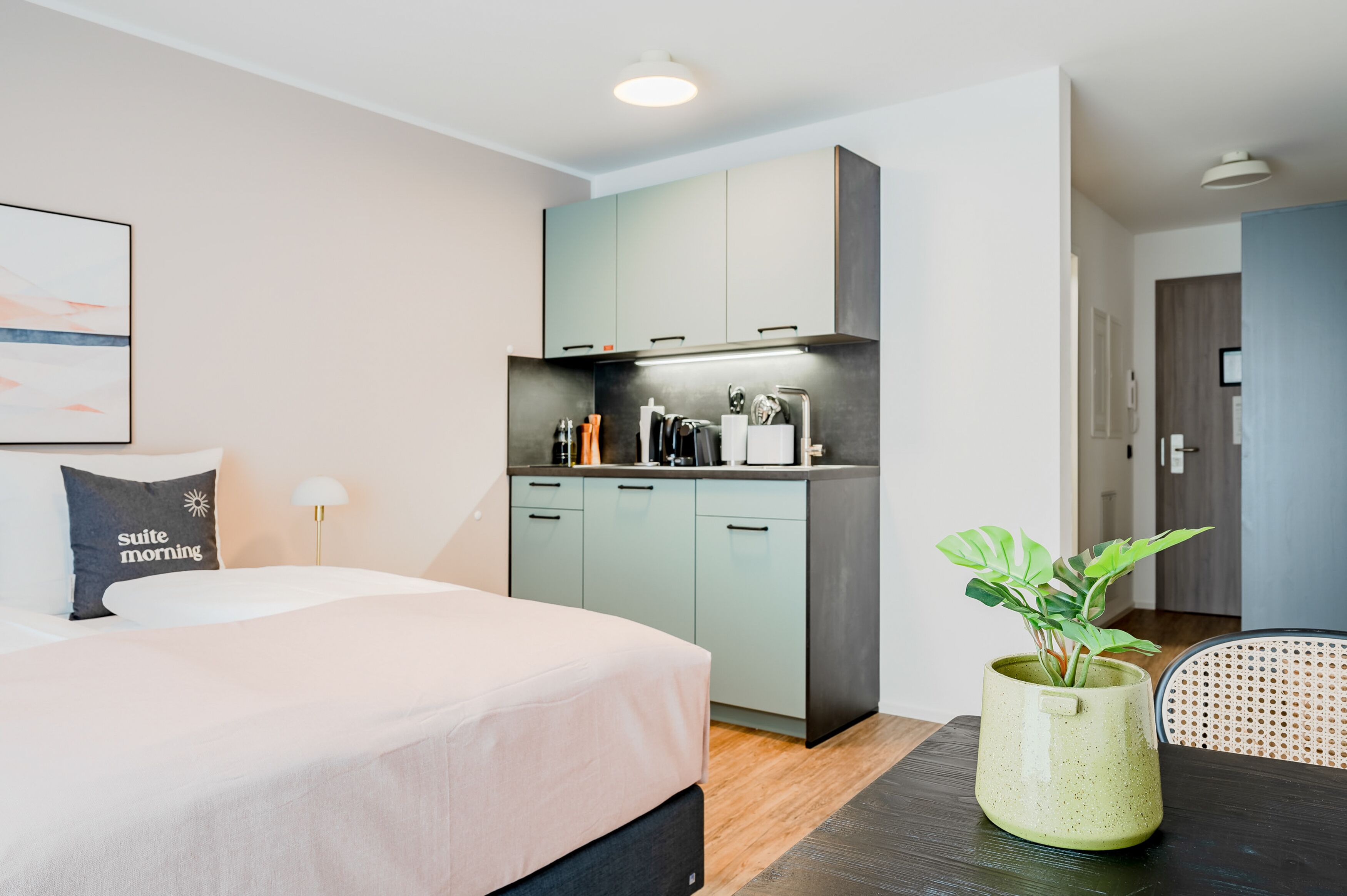 Ein kleines Hotelzimmer mit Bett, Küchenzeile und Essecke.