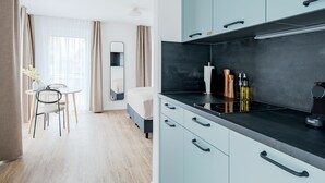 Una habitación de hotel moderna con kitchenette, zona de comedor y cama.
