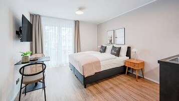 A modern bedroom with a bed, bedside table, TV, and a desk with a chair.