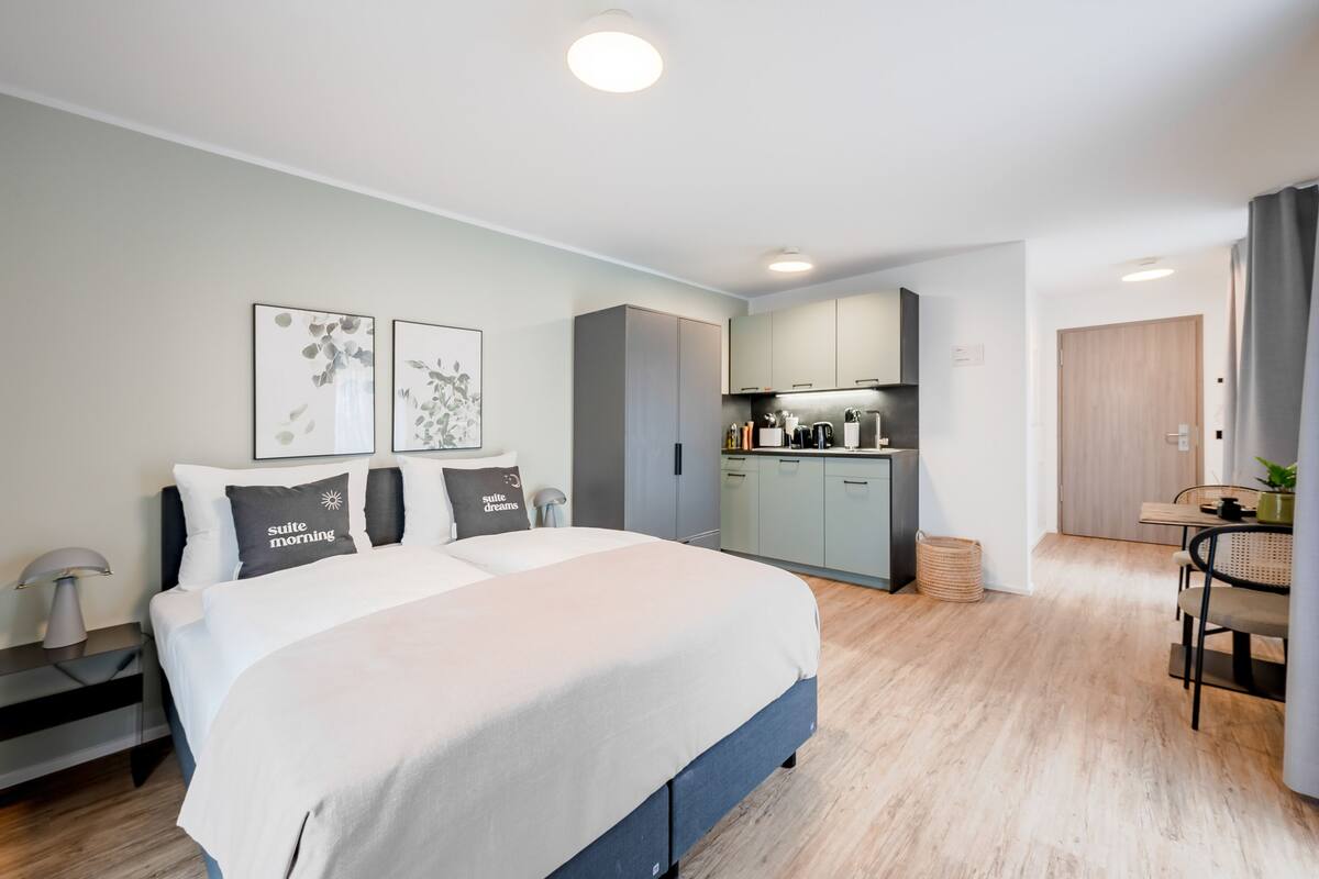 Una habitación de hotel moderna con una cama grande, un rincón de cocina y un comedor.