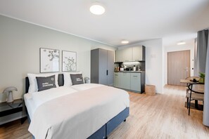 A modern hotel room with a large bed, a kitchenette, and a dining area. - Limehome Metzingen Wilhelmstr. (Metzingen)