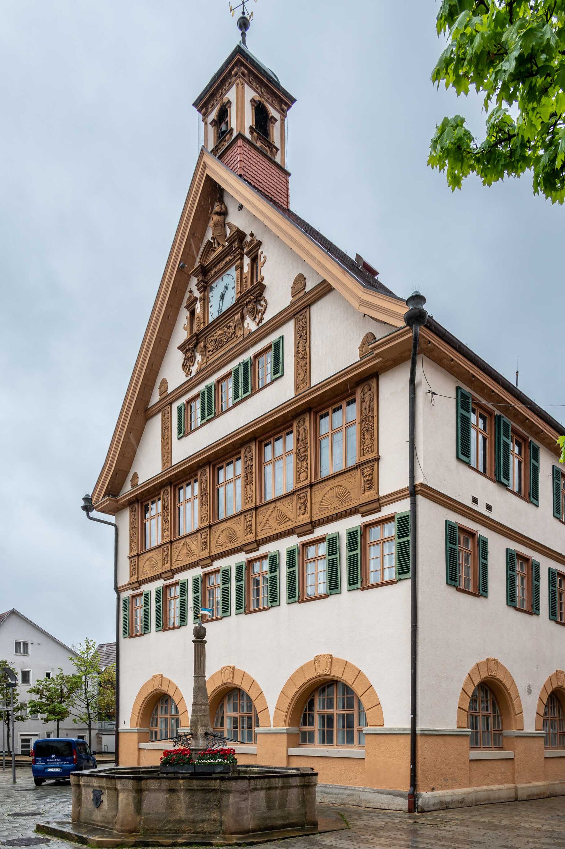 Un edificio histórico con una torre de reloj, ventanas arqueadas y una fuente en primer plano.