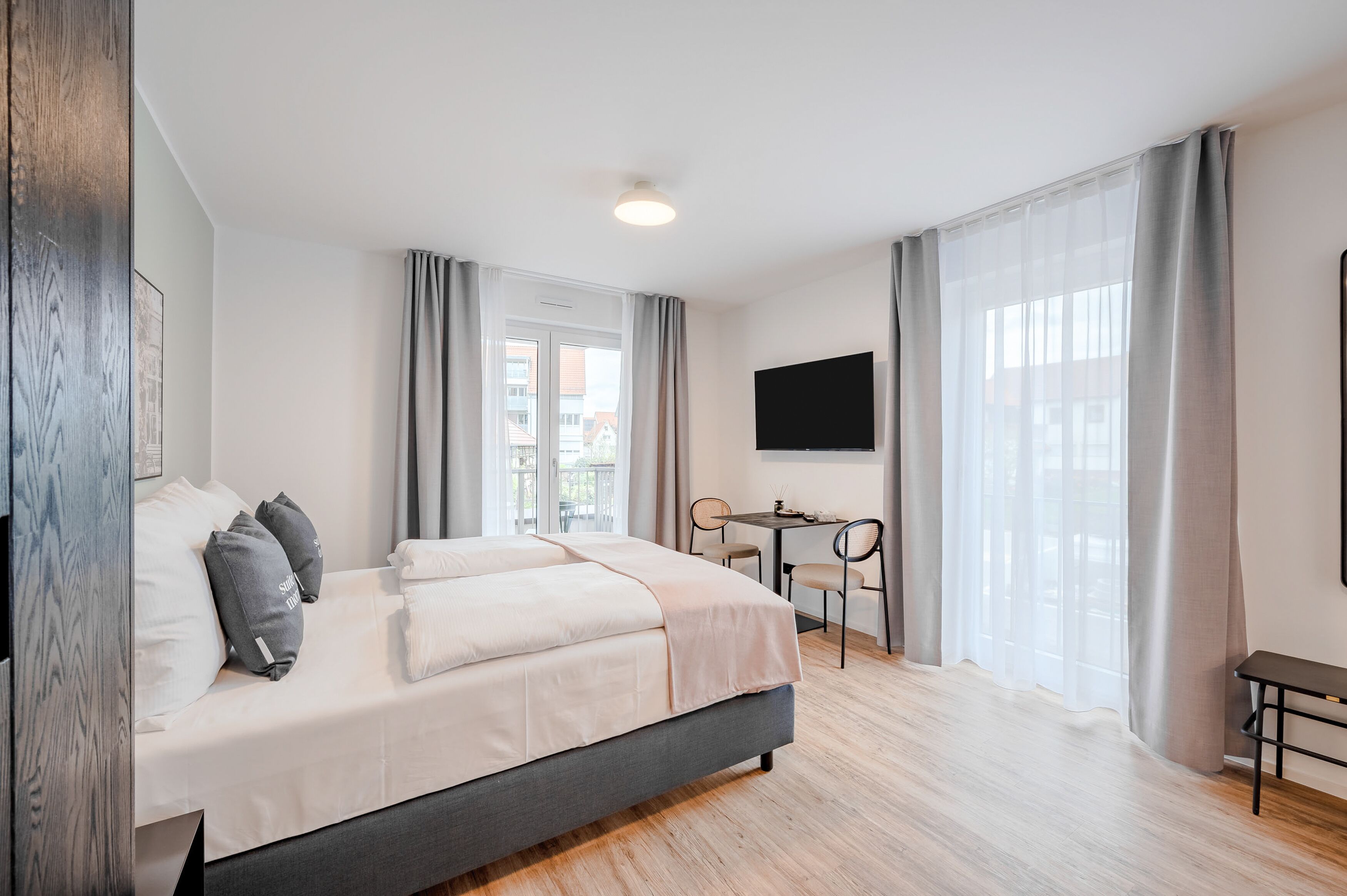 A modern hotel room with a large bed, a desk, and a TV.