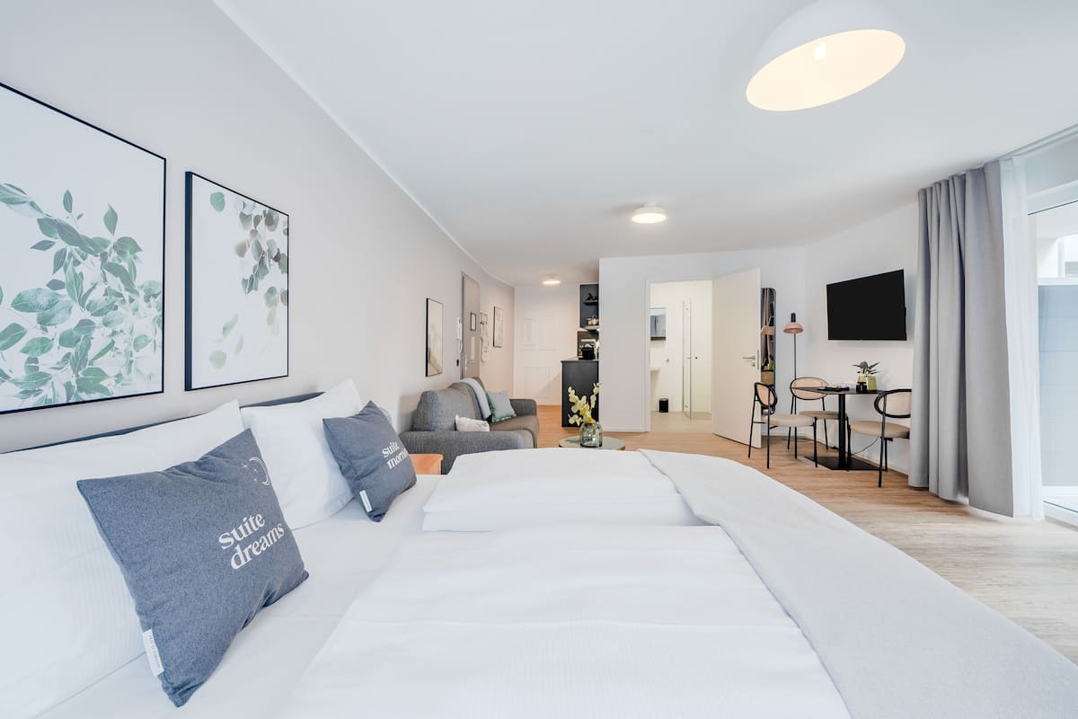 Una habitación de hotel moderna con una cama grande, un sofá, un comedor y obras de arte en las paredes.