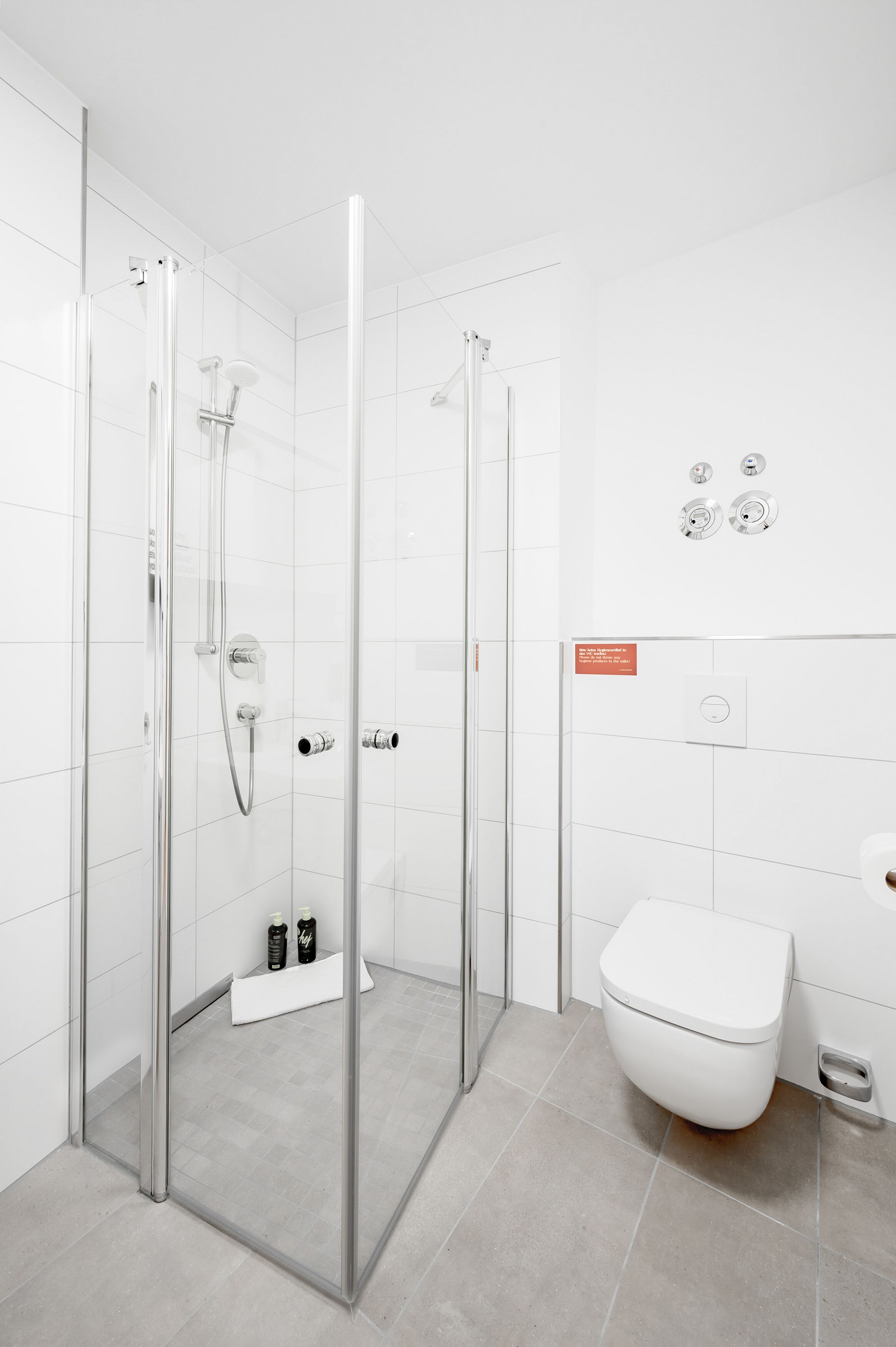 A modern bathroom with a glass-enclosed shower, a white toilet, and a sink.