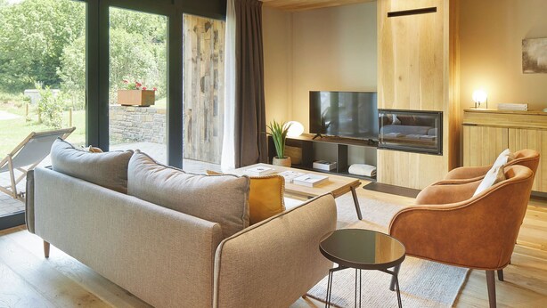 A modern living room with a sofa, armchairs, a coffee table, and a TV.
