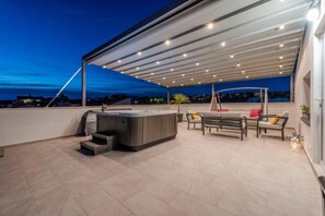 A rooftop terrace with a hot tub, outdoor seating, and a covered area with lights. - Luxury Majpruz Suites I (Zadar)
