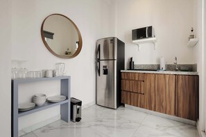 A modern kitchen with a stainless steel refrigerator, wooden cabinets, a microwave, and a marble-tiled floor.