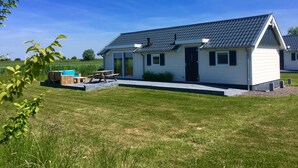 A small, single-story house with a dark roof, a front door, and a patio with a table and chairs. - Chalet for 4 persons in Kamperland, close to beach and sea (kamperland)