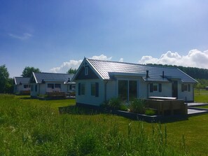 A row of small, single-story houses with sloped roofs, surrounded by a grassy field. - Chalet for 4 persons in Kamperland, close to beach and sea (kamperland)