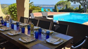 Un área de comedor al aire libre con vista al mar y una piscina.