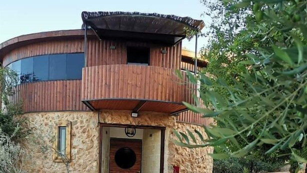 A modern, circular building with a wooden exterior and a stone facade. It features a central entrance with steps leading up to a wooden door. - Olive Palace Restaurant and Lounge  (al-Khader)
