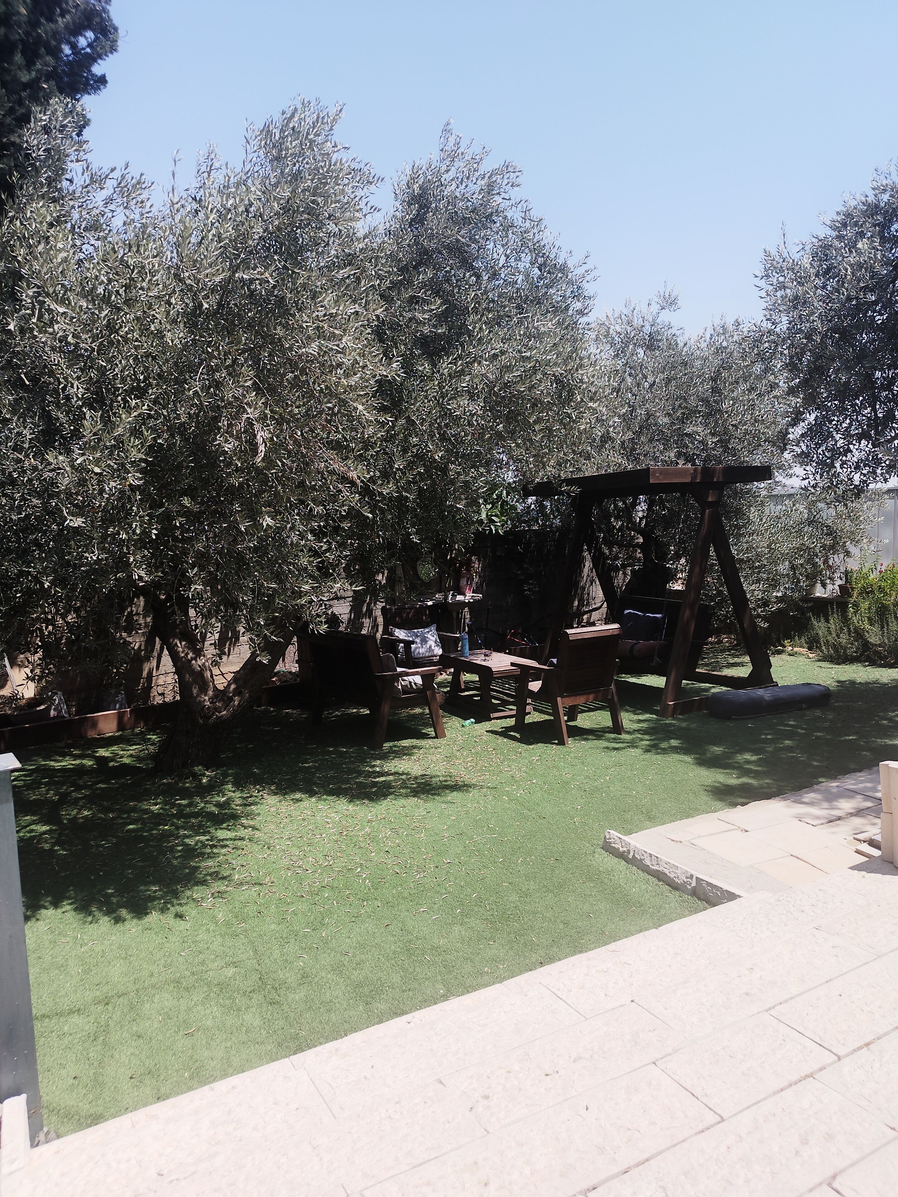 A patio area with a wooden swing set, a table, and chairs.