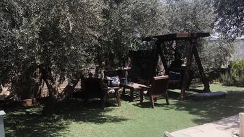 A patio area with a wooden swing set, a table, and chairs.