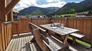 A wooden deck with a picnic table and benches, overlooking a mountainous landscape.