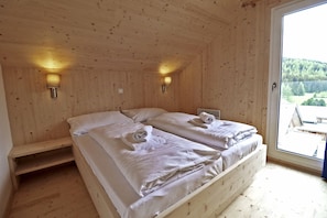 Ein Holzhütten-Zimmer mit zwei Betten, einer Bank und zwei Wandleuchten.