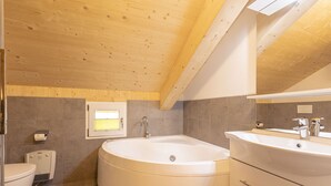 A modern bathroom with a freestanding bathtub, a vanity with a mirror, and a toilet.