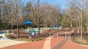Un parc doté d’une allée pavée, d’arbres et d’un pavillon au toit bleu.