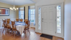 Une salle à manger avec une table dressée pour quatre personnes, des chaises en bois, un lustre et une porte blanche avec une fenêtre.