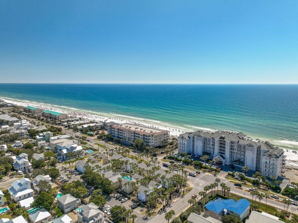 An aerial view of a coastal area with beachfront hotels, roads, and a beach.