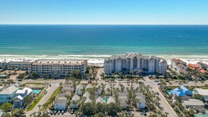 A coastal hotel with multiple buildings, a beachfront, and a parking area with palm trees. - Destin Entire Crystal Beach Cottage~Steps to Beach & Pool~Prime Location (Destin)