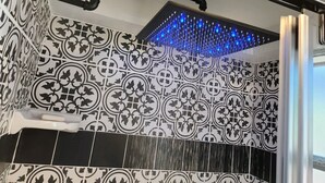 Chuveiro com parede estampada em preto e branco, cano preto e luzes LED azuis.