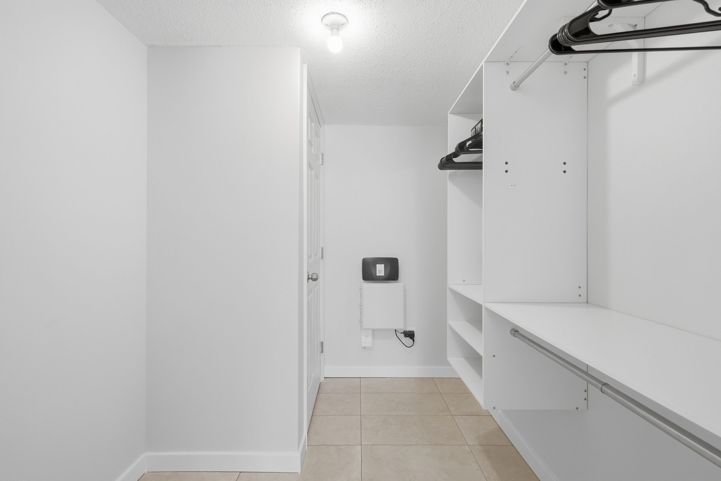Un placard blanc avec les portes ouvertes, un luminaire et une prise de courant.
