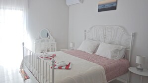 Un dormitori ben organitzat amb llit, taules de nit, un mirall i un quadre a la paret.