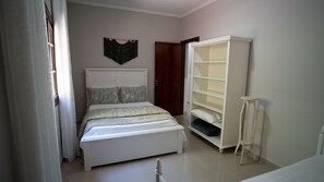 A bedroom with a bed, a wardrobe, and a bedside table. - Pousada Boutique Mercedes (Extrema)