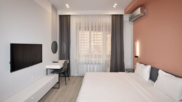Une chambre d’hôtel moderne dotée d’un grand lit, d’un bureau avec une chaise, d’un téléviseur à écran plat et d’un système de climatisation.